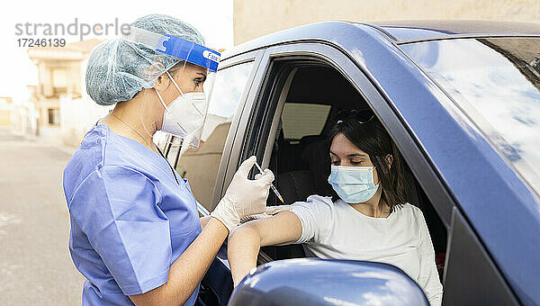 Mittlere erwachsene Frau wird im Auto von einer Ärztin geimpft