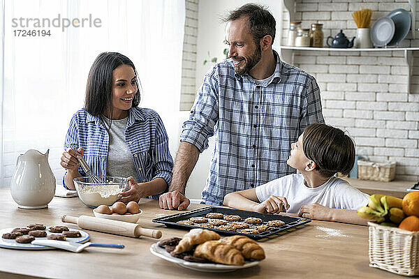 Familie diskutiert bei der Zubereitung von Essen in der Küche zu Hause