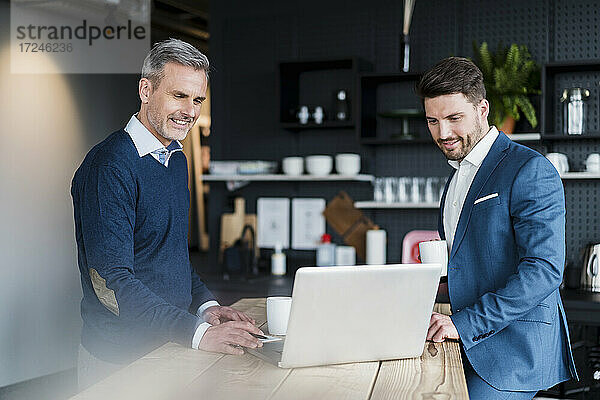 Geschäftsleute arbeiten an einem Laptop in einem Bürocafé