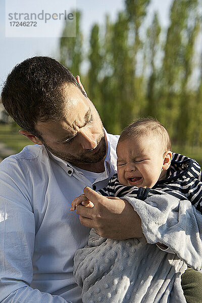 Vater tröstet weinenden kleinen Jungen im Park