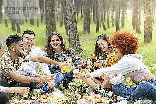 Fröhliche männliche und weibliche Freunde genießen die Party beim Picknick im Wald