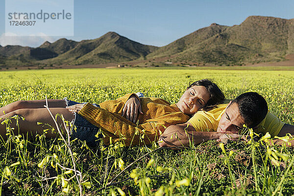 Junges Paar im Gras liegend auf einer Wiese