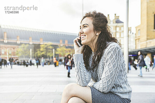 Lächelnde Geschäftsfrau  die in der Stadt mit einem Mobiltelefon spricht