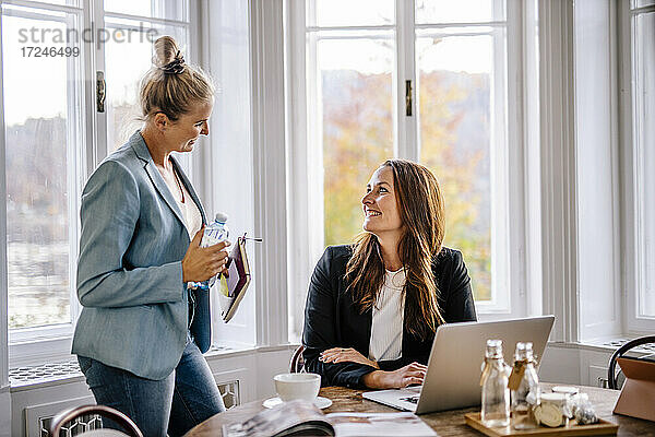 Lächelnde Geschäftsfrauen im Gespräch mit einer Kollegin im Büro