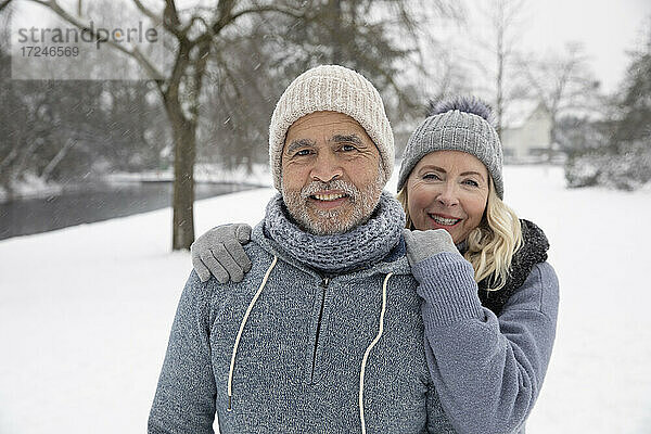 Lächelnde Frau in warmer Kleidung steht mit Mann im Park