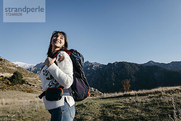 Glückliche Frau mit Rucksack am Berg stehend