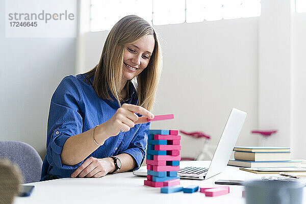 Lächelnde Geschäftsfrau  die im Büro ein Blockentfernungsspiel spielt