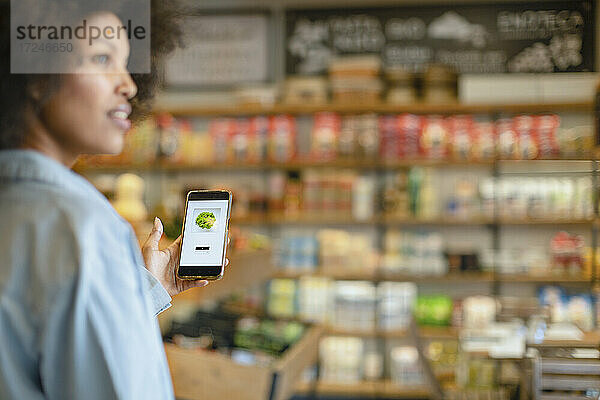 Frau kauft Gemüse über eine mobile Anwendung im Supermarkt