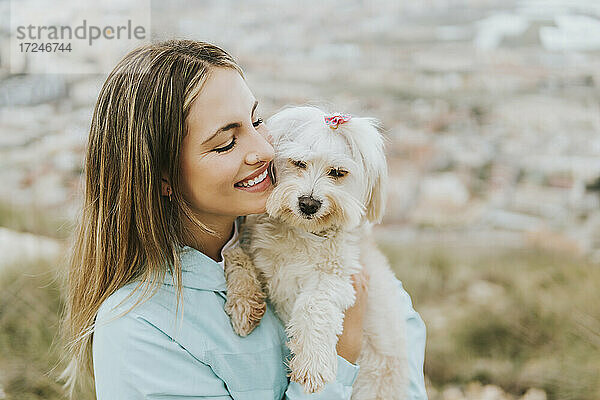 Schöne Frau lächelt  während sie einen Hund umarmt