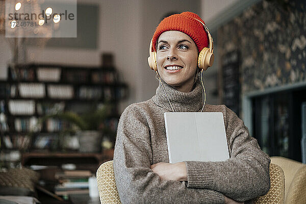 Mittlere erwachsene Frau mit digitalem Tablet  die im Café über Kopfhörer Musik hört