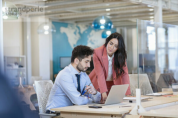 Männliche und weibliche Unternehmer besprechen einen Geschäftsplan auf einem Laptop in einem Coworking-Büro