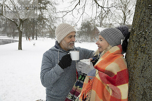 Älteres Paar  das sich im Winter mit einer Tasse in der Hand unterhält