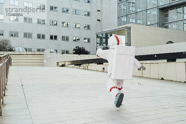 Astronautin läuft auf der Promenade vor einem Gebäude in der Stadt