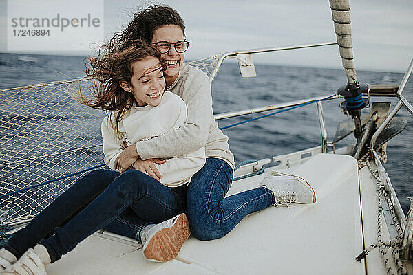 Fröhliche Mutter  die ihre Tochter umarmt  während sie auf einem Segelboot unterwegs ist