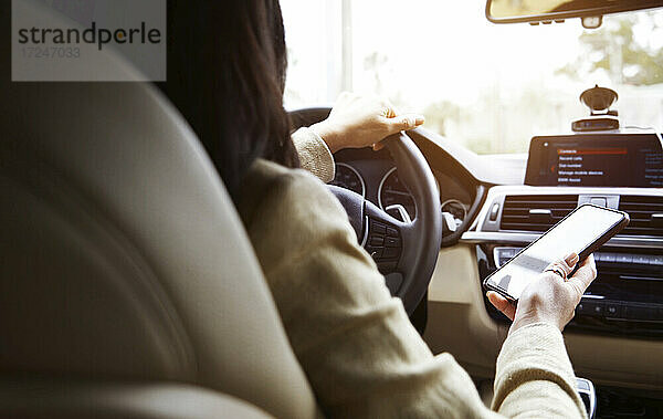 Frau benutzt Smartphone beim Autofahren