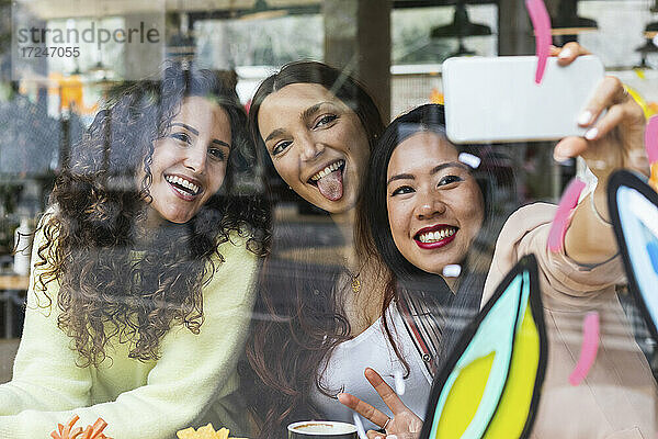 Fröhliche Freunde machen ein Selfie mit ihrem Handy in einem Cafe