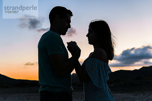 Paar hält sich bei Sonnenuntergang im Freien an den Händen