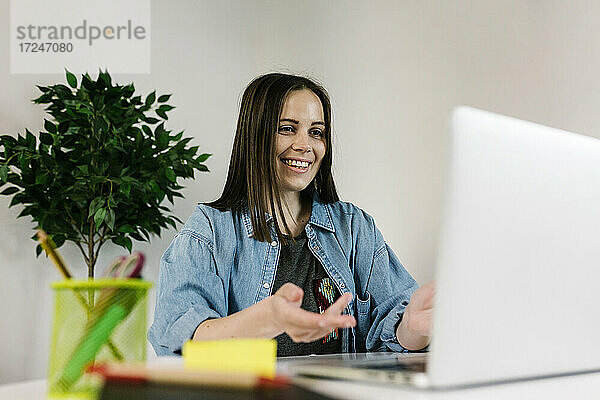 Lächelnde Unternehmerin im Gespräch während einer Videokonferenz über einen Laptop zu Hause