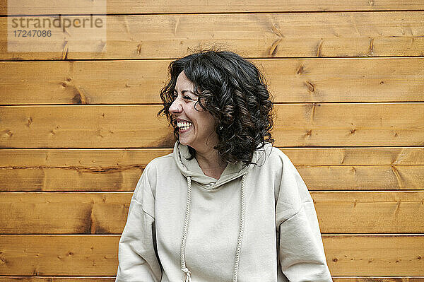 Lächelnde Frau vor einer Holzwand