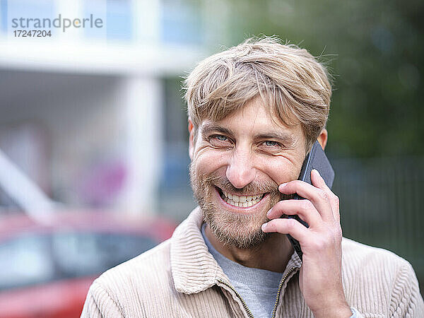 Lächelnder Mann  der mit einem Smartphone spricht