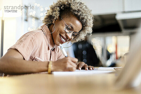 Geschäftsfrau mit Brille schreibt bei der Arbeit im Home Office