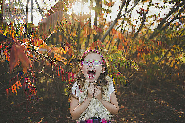 Heiteres Mädchen mit offenem Mund vor Pflanzen im Herbst