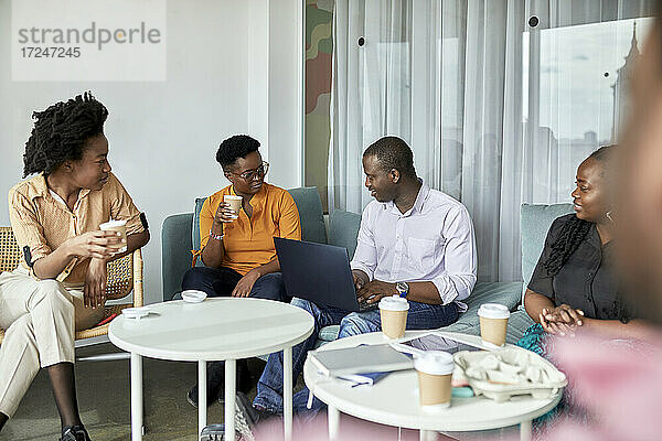 Männliche und weibliche Unternehmer unterhalten sich bei einem Kaffee im Coworking-Büro