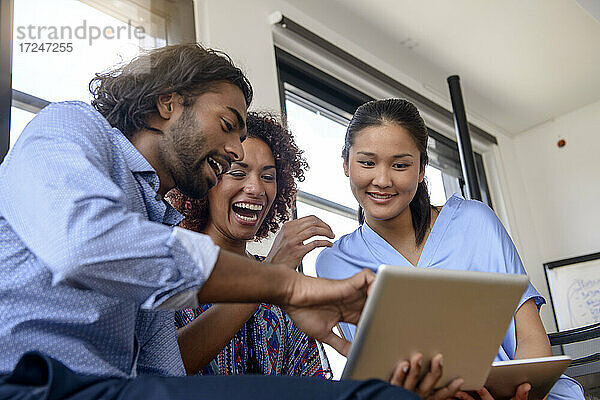 Internationale Studentinnen und Studenten lächeln bei der Nutzung eines digitalen Tablets in der Universität