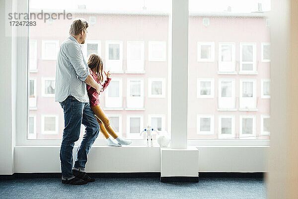 Vater spielt mit Tochter am Fenster zu Hause