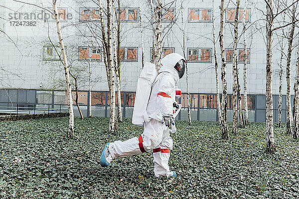 Junge Astronautin geht im Garten in der Nähe eines Gebäudes spazieren