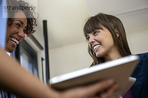 Lächelnde Unternehmerinnen schauen sich im Büro an