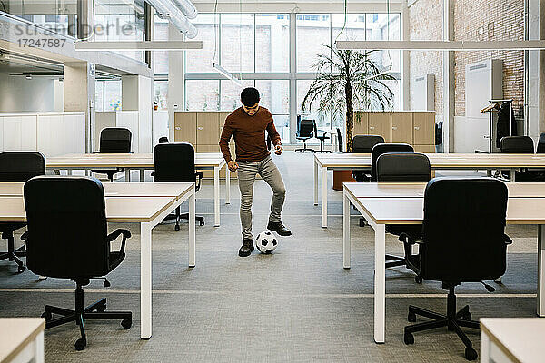 Junger Unternehmer spielt mit Fußball im Büro