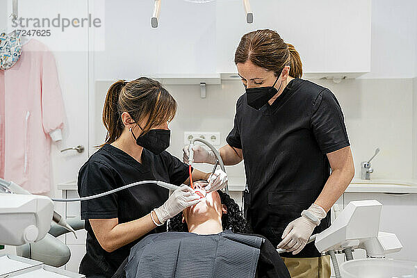 Zahnärztinnen beim Absaugen von Patienten in einer Klinik während der Pandemie