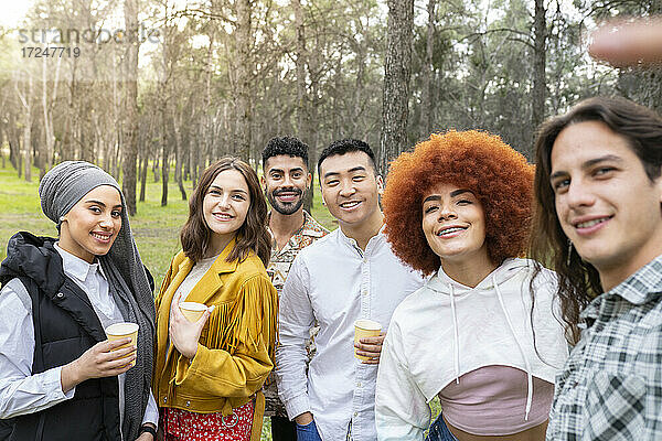 Multi-ethnische männliche und weibliche Freunde nehmen Selfie beim Genießen im Wald