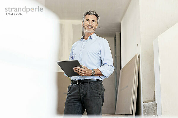 Männlicher Fachmann mit digitalem Tablet auf einer Baustelle