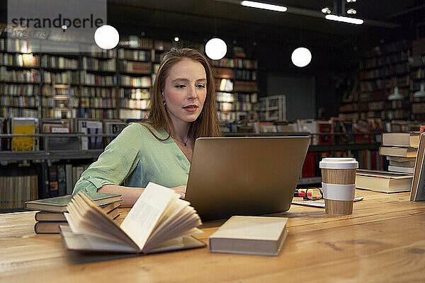 Schöne Frau  die einen Laptop benutzt und in einer Bibliothek studiert