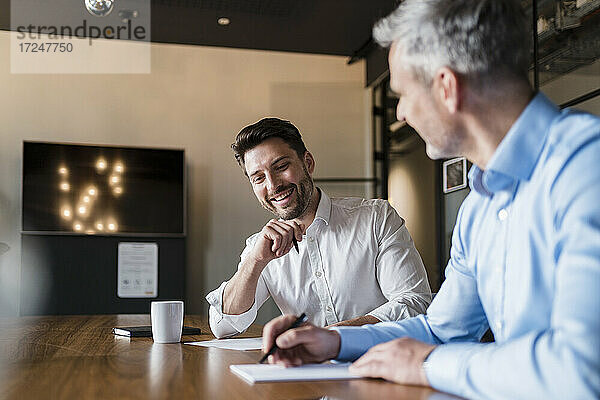 Lächelnde Geschäftsleute mit Papierdokumenten im Sitzungssaal