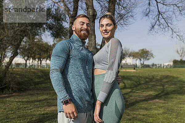 Lächelndes junges Paar im öffentlichen Park stehend