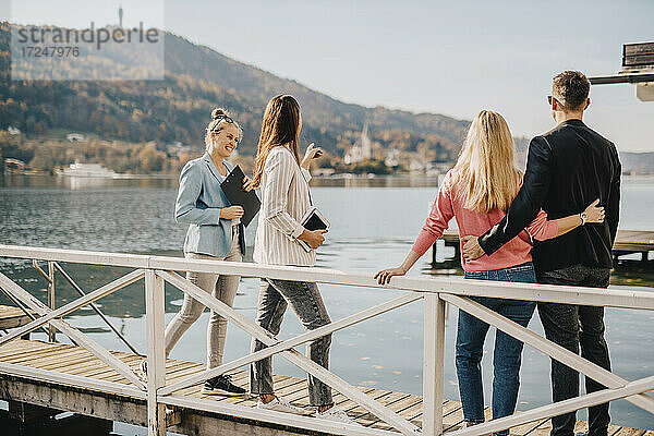 Geschäftsfrauen mit Paar auf Steg am See