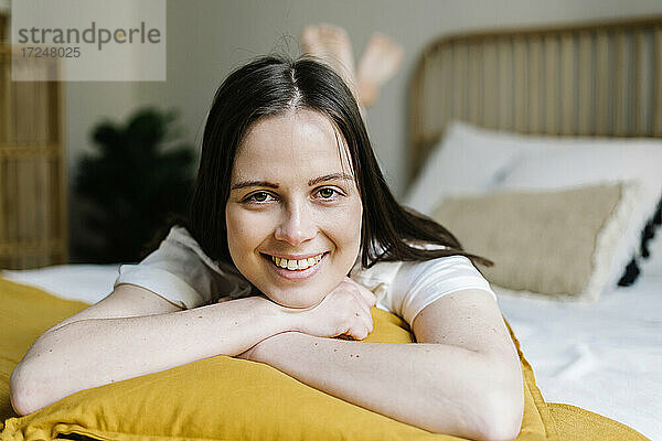 Lächelnde Frau auf dem Bett liegend zu Hause