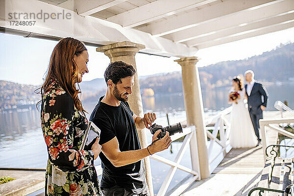 Fotograf und Hochzeitspaar auf dem Steg über dem See