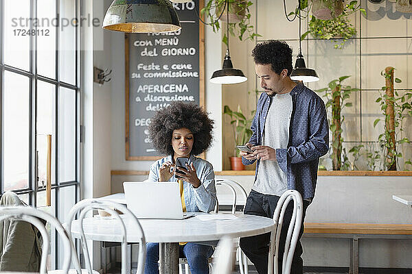 Männliche und weibliche Unternehmer nutzen Smartphones im Café
