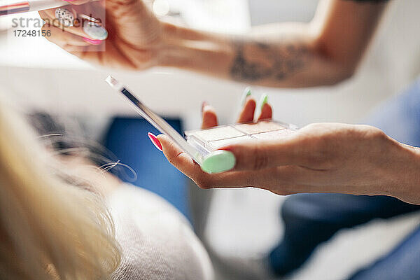 Make-up-Künstlerin trägt Highlighter auf ein Modell im Studio auf