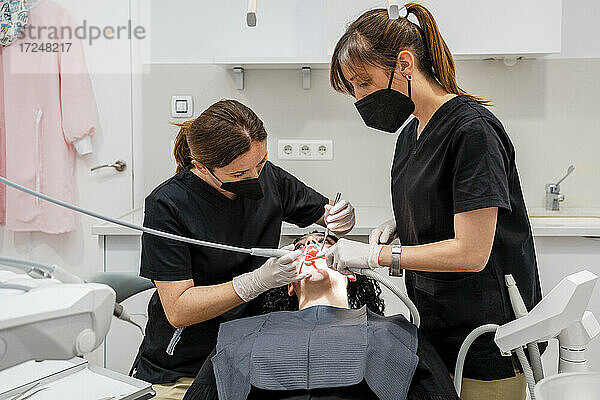 Zahnärztinnen reinigen die Zähne eines Patienten in einer medizinischen Klinik