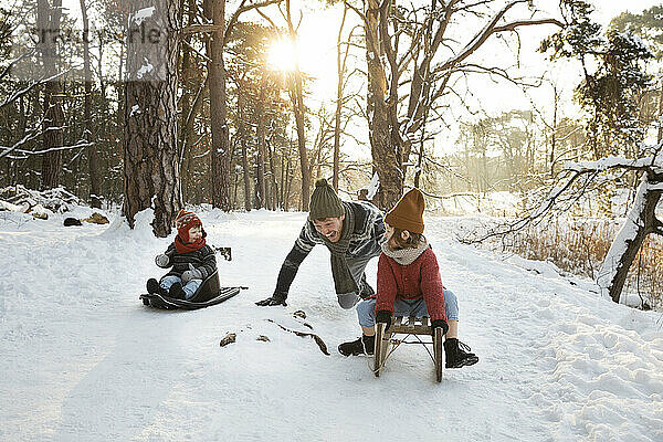Vater spielt mit Söhnen im Winter im Schnee