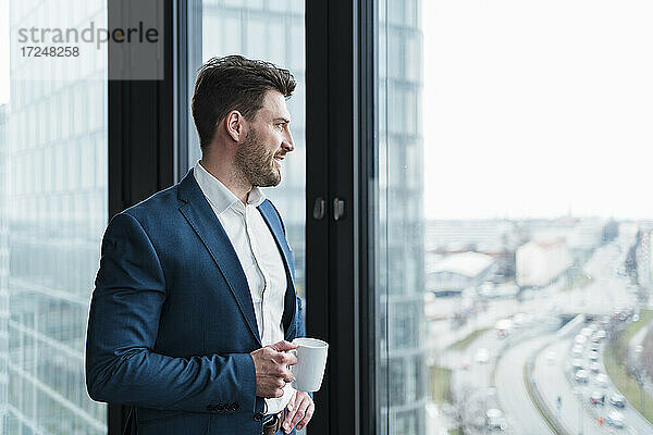 Geschäftsmann mit Kaffeetasse träumt Tag am Fenster bei der Arbeit Platz