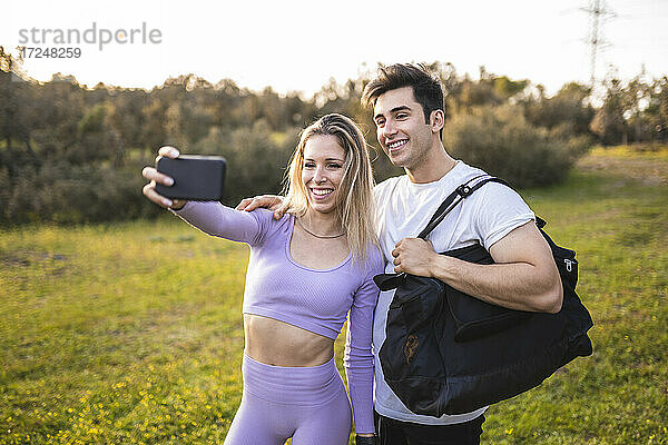 Lächelnde Athleten  die bei Sonnenuntergang ein Selfie mit ihrem Mobiltelefon machen