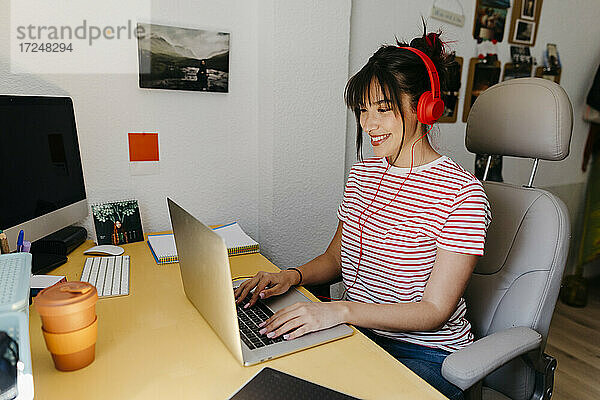 Frau mit Kopfhörern bei der Arbeit am Laptop im Heimbüro