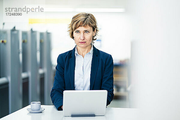 Nachdenkliche Geschäftsfrau mit digitalem Tablet in einer Druckerei