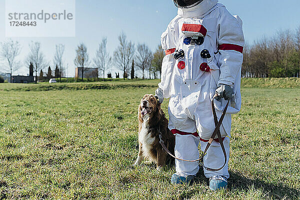 Astronaut stehend mit Haustier im Gras an einem sonnigen Tag